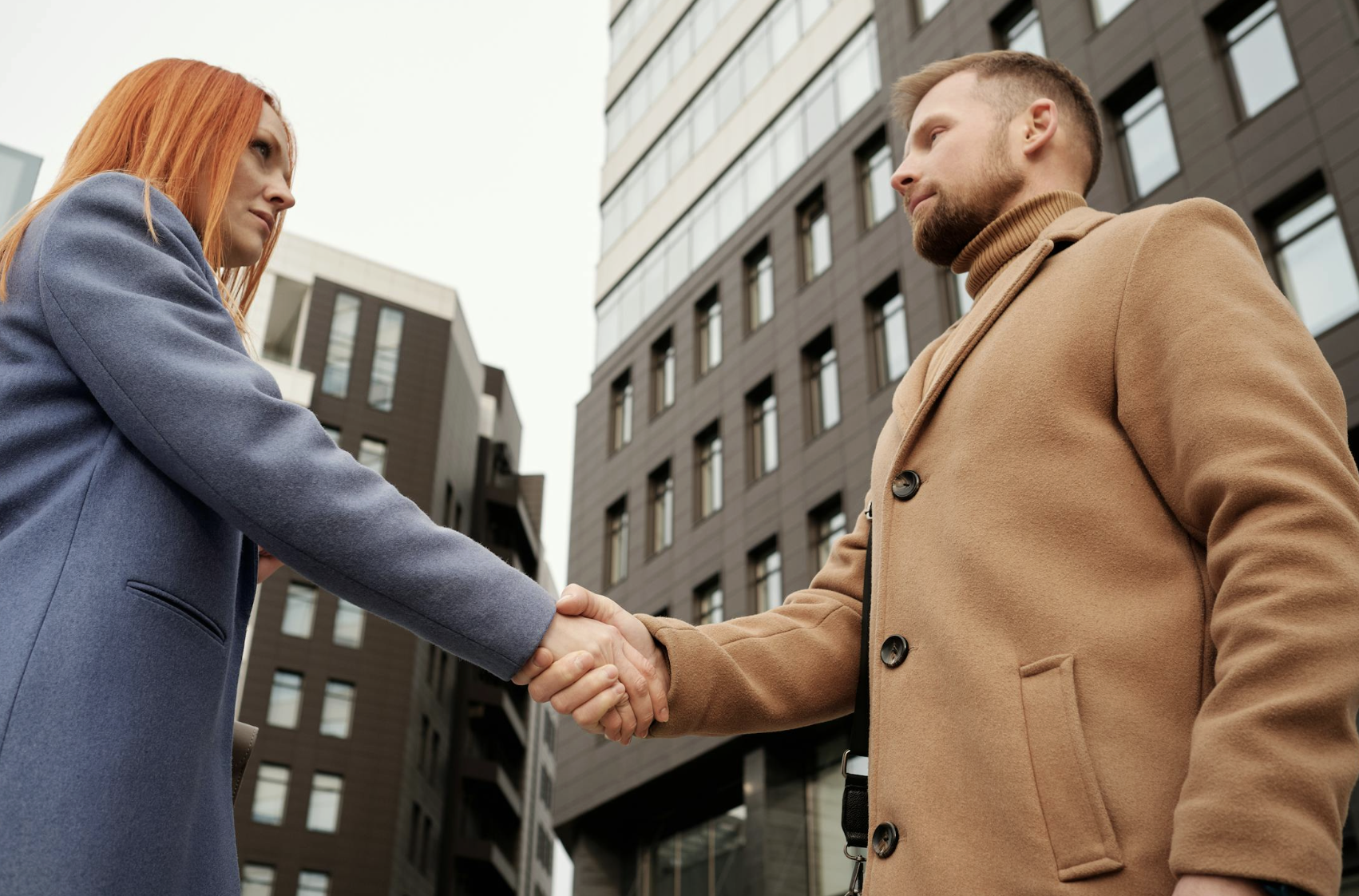 This photo shows two people shaking hands outside an apartment building.